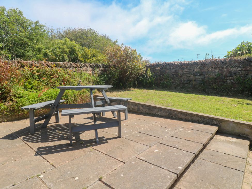 A garden with a table and benches on a patio at Yonde View Camborne
