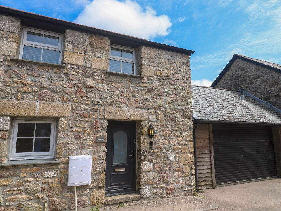 An outdoor view of a stone house with a garage at Gews Farm Lodge St Just