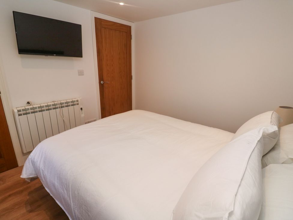A bedroom with a bed and television at Gews Farm Lodge St Just