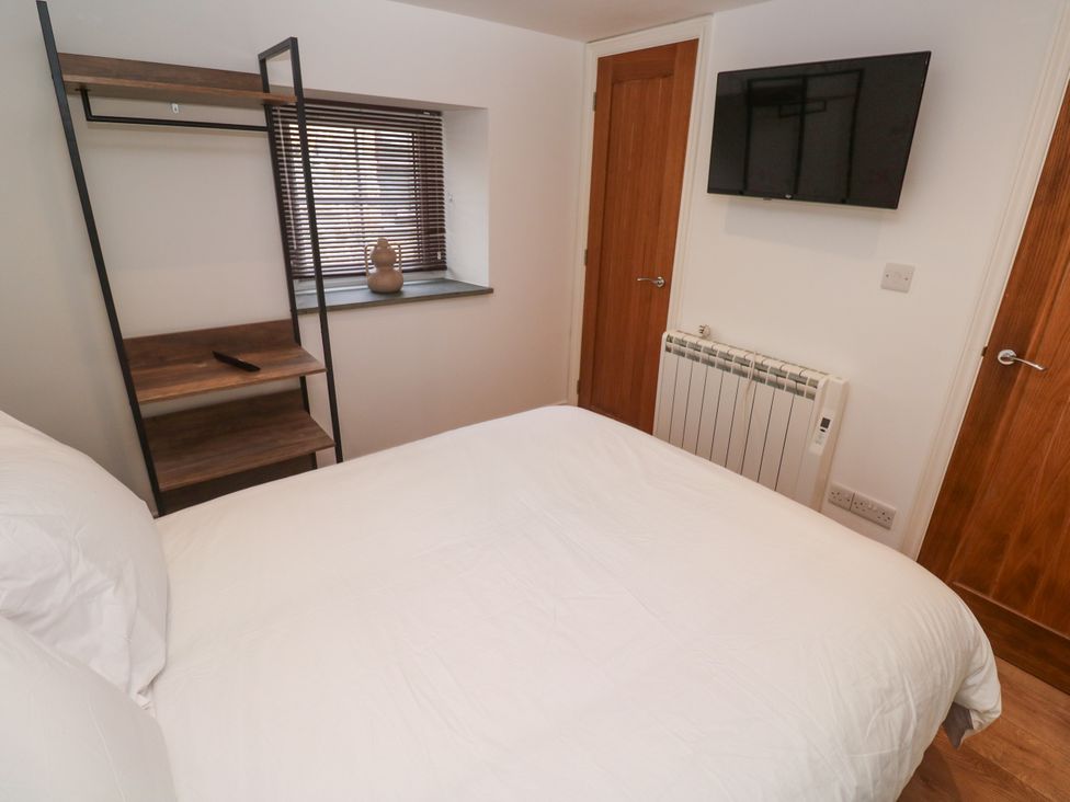 A bedroom with a bed and a shelf at Gews Farm Lodge in St Just