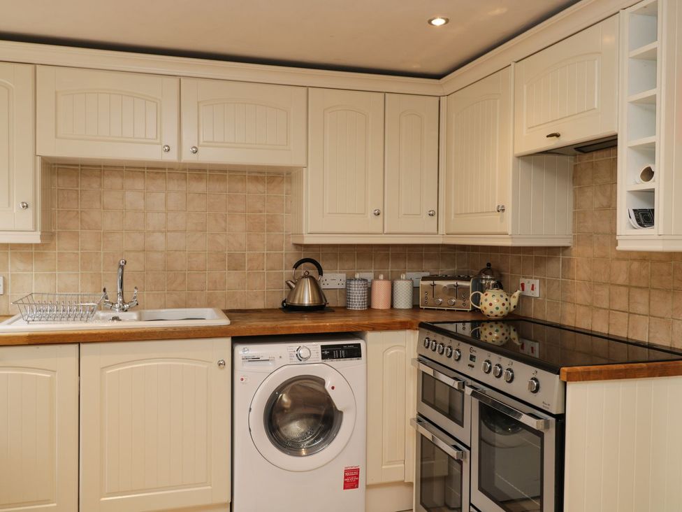 A kitchen with a sink and washing machine at The Old Barn in Hereford