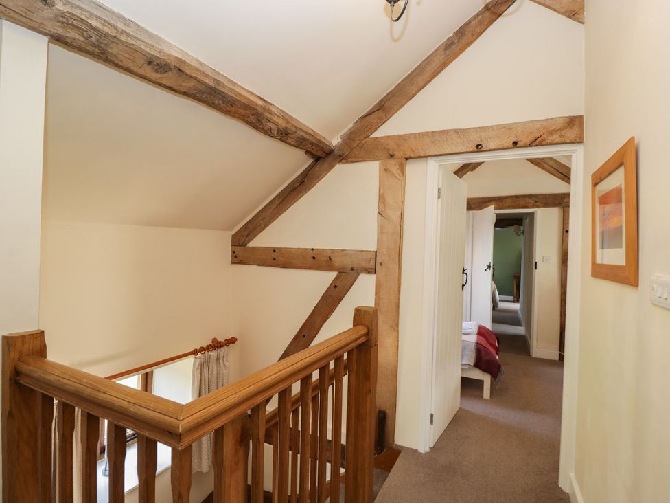 A hallway with wooden railings and a door at The Old Barn in Hereford