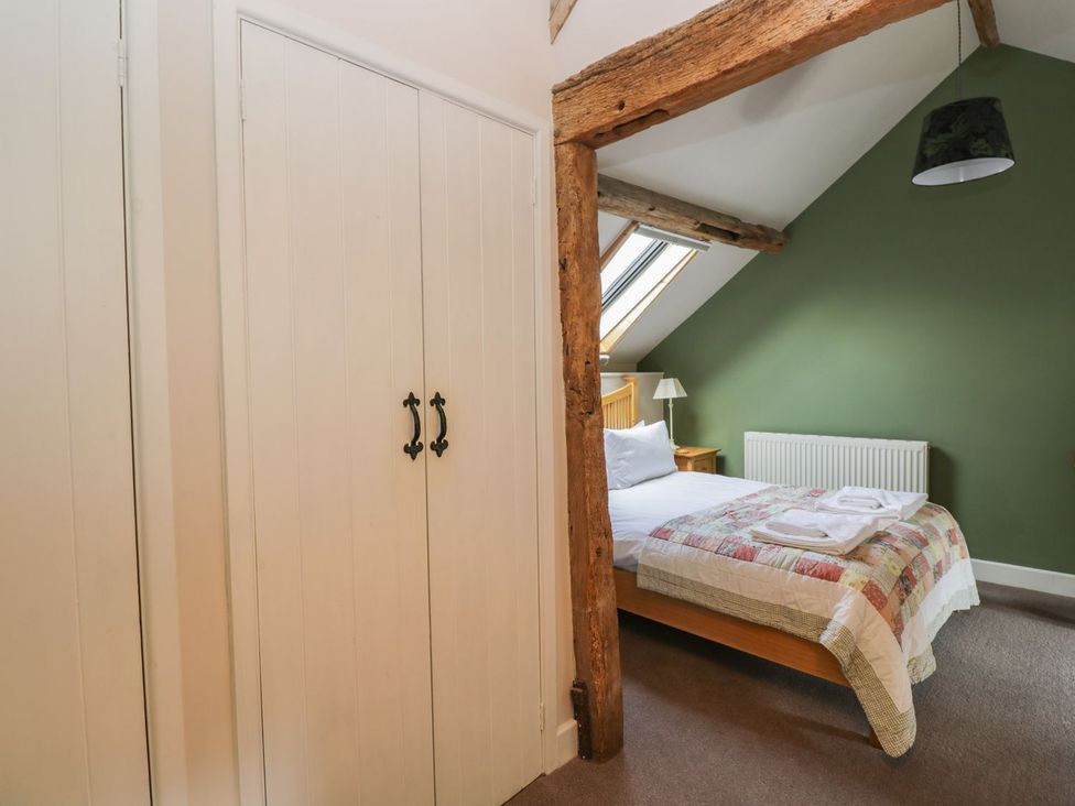 A bedroom with a bed and bedside table at The Old Barn in Hereford