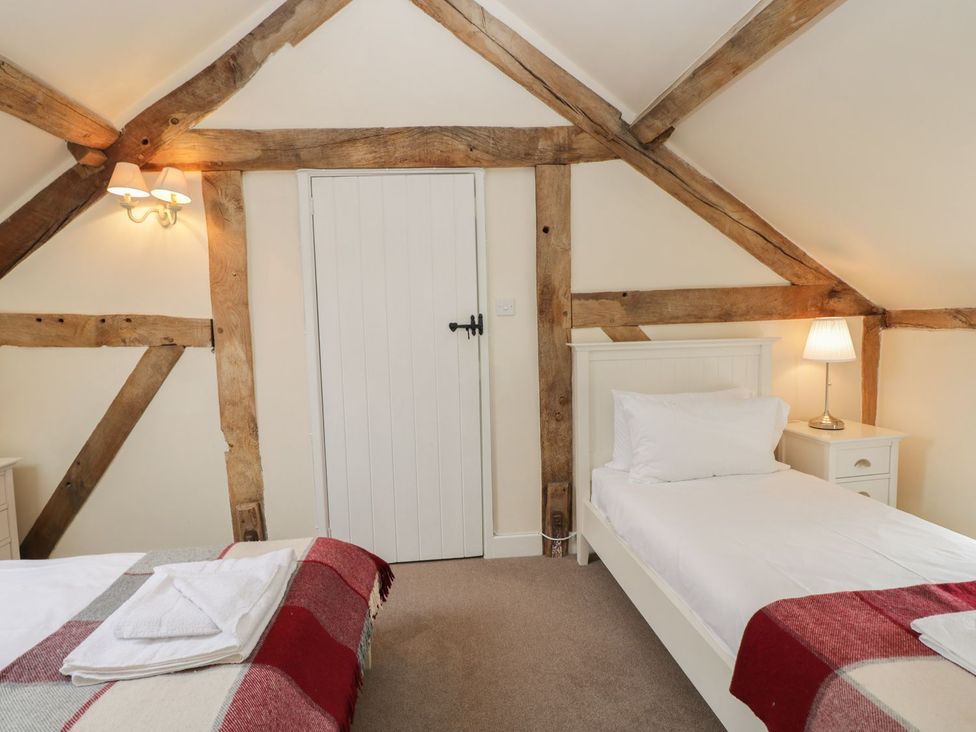 A bedroom with two beds and a door at The Old Barn in Hereford