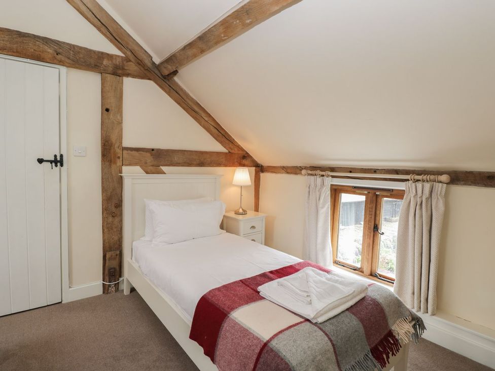 A bedroom with a bed, lamp, and window at The Old Barn in Hereford