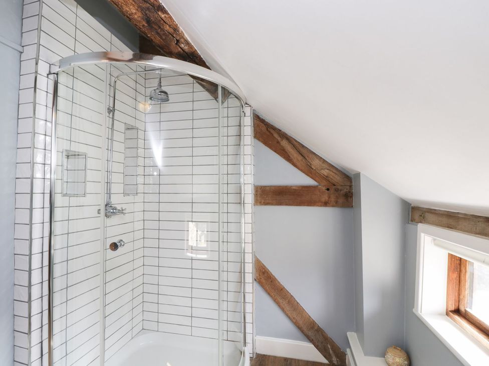 A bathroom with a shower and wooden beams at The Old Barn in Hereford