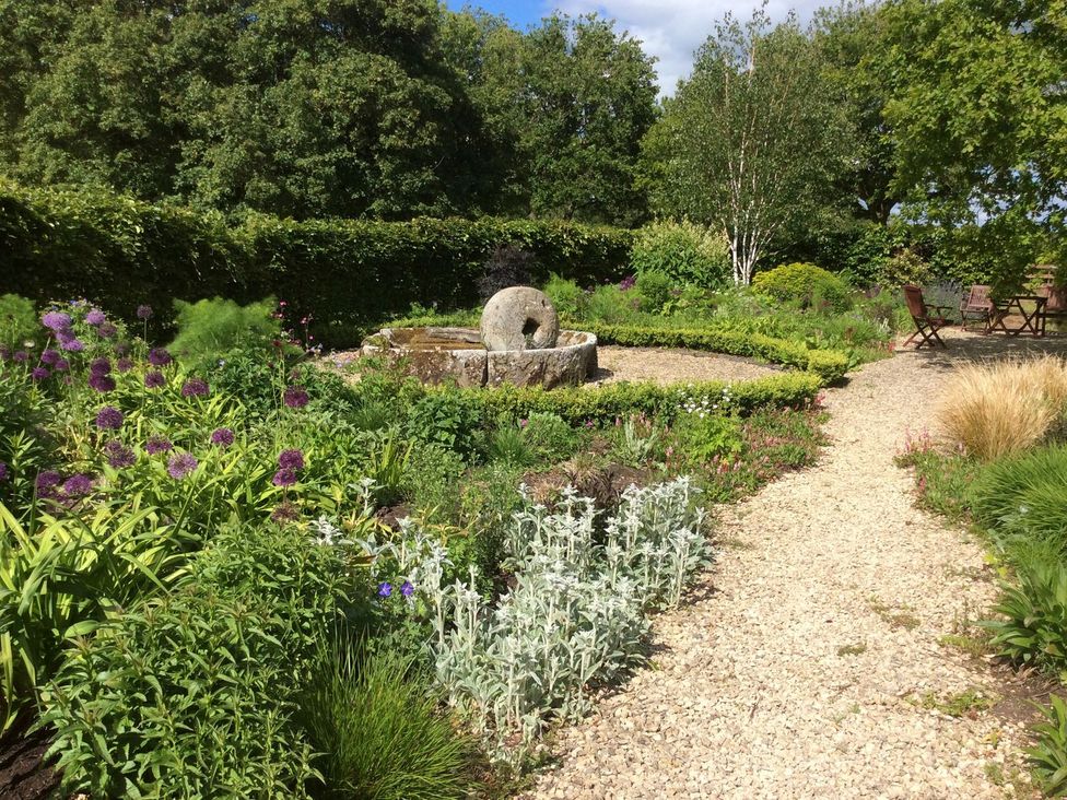 A garden with flowers, a fountain, and seating at The Old Barn in Hereford