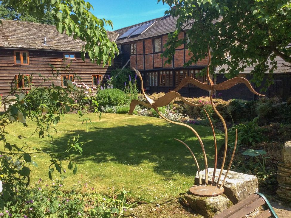 A garden with a sculpture and buildings at The Old Barn in Hereford