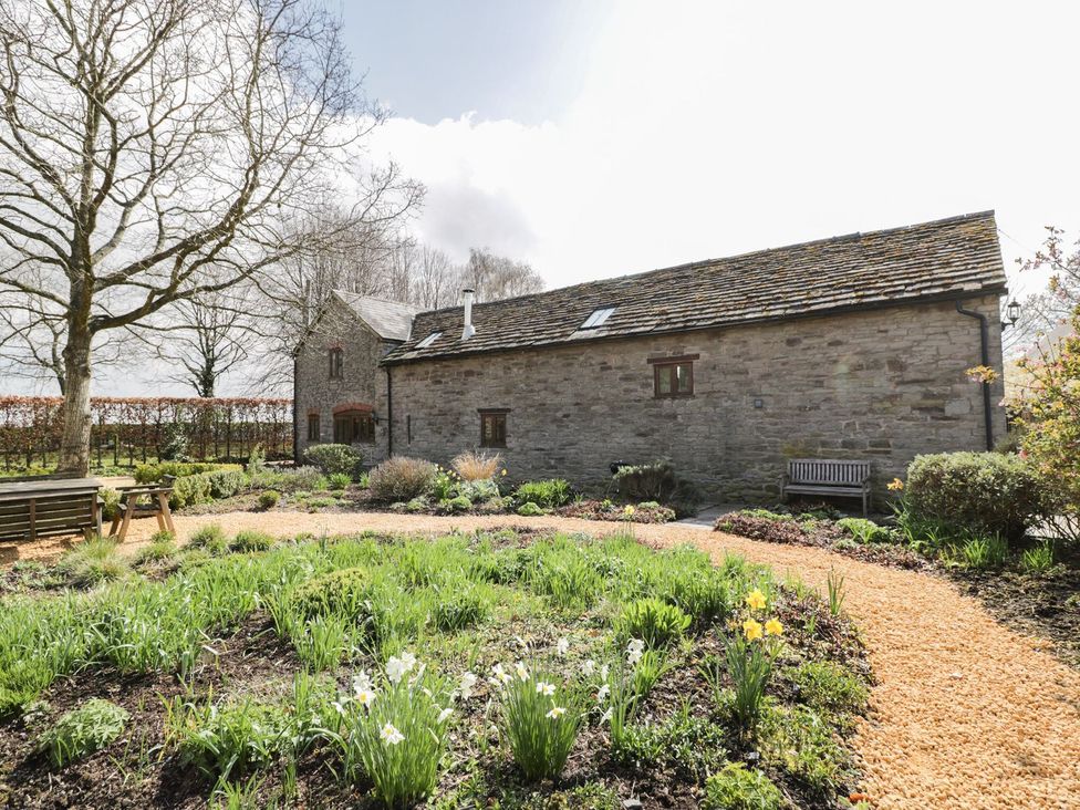 A garden area with a stone building and plants at The Old Barn in Hereford
