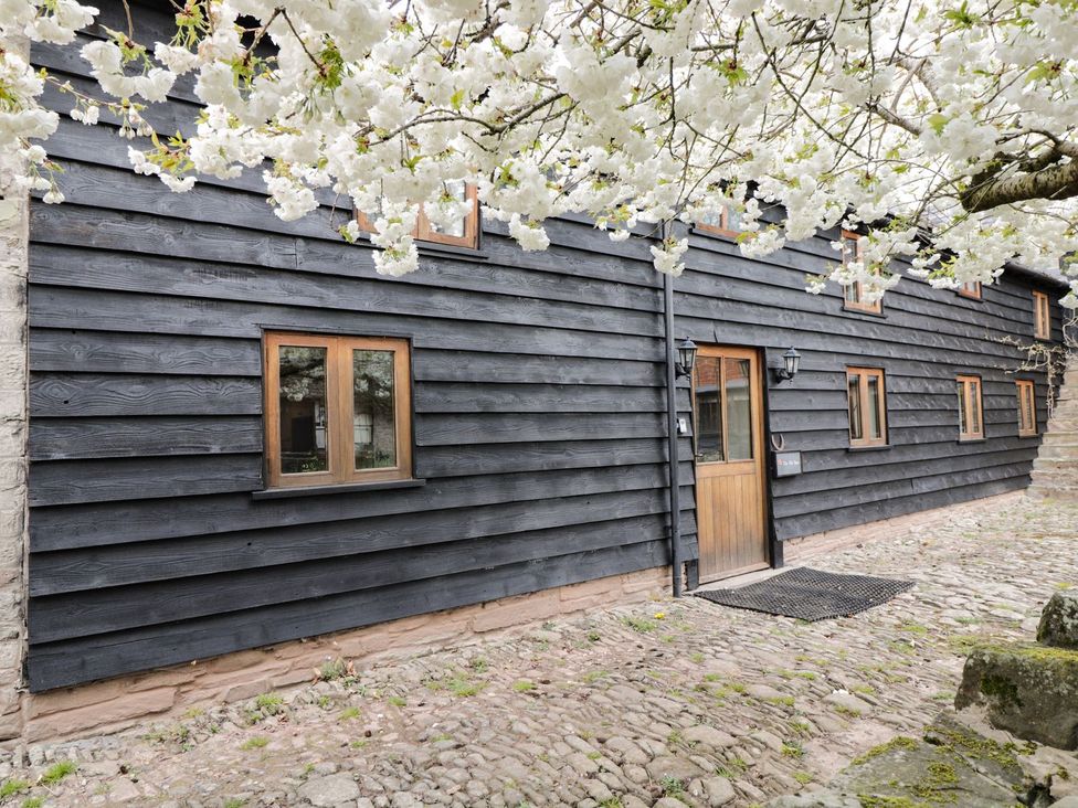 An outdoor view of a black wooden building with windows at The Old Barn in Hereford