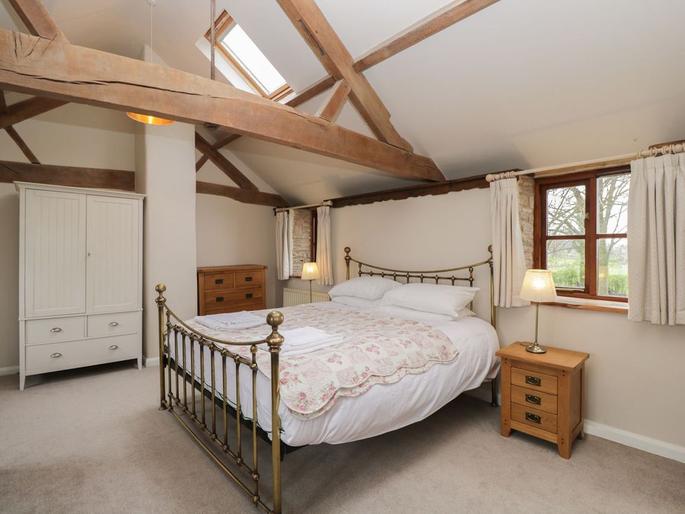 A bedroom with a bed, wardrobe, nightstand, and lamp at The Granary in Hereford