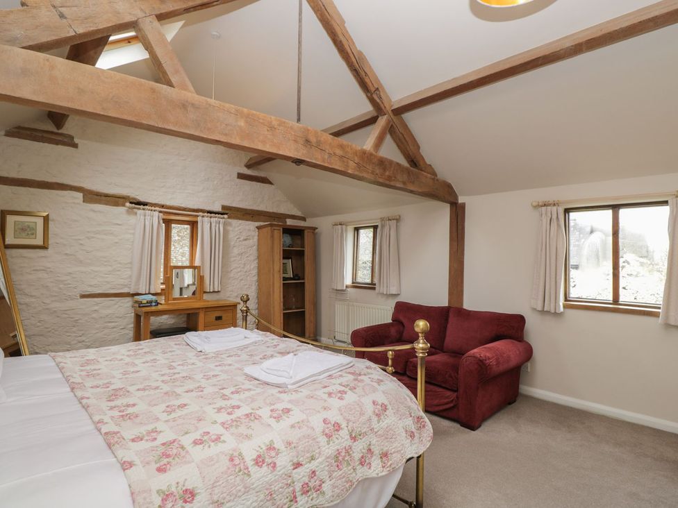 A bedroom with a bed and armchair at The Granary in Hereford