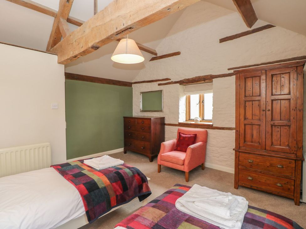 A bedroom with two beds and a wardrobe at The Granary in Hereford