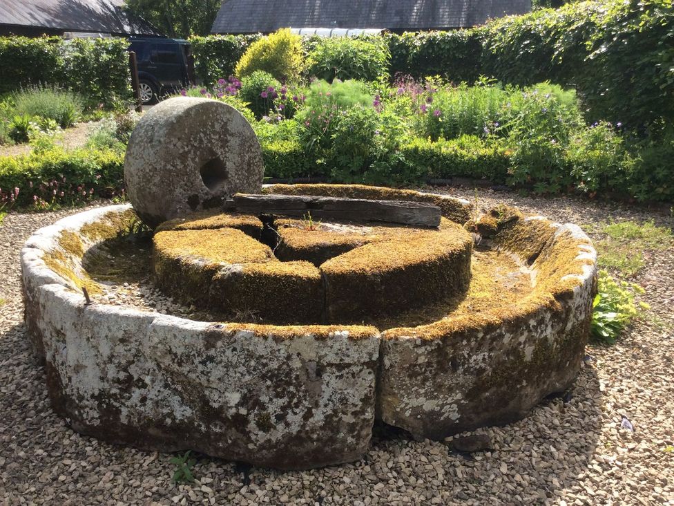 A stone mill wheel in a garden at The Granary in Hereford