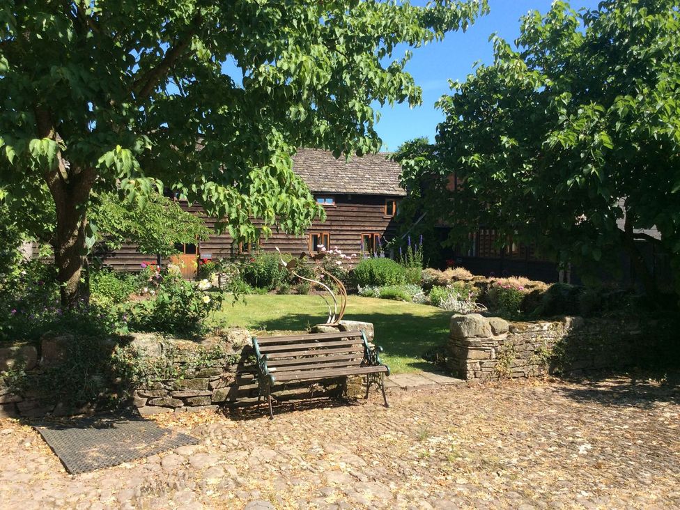 A garden with a bench and trees at The Granary in Hereford