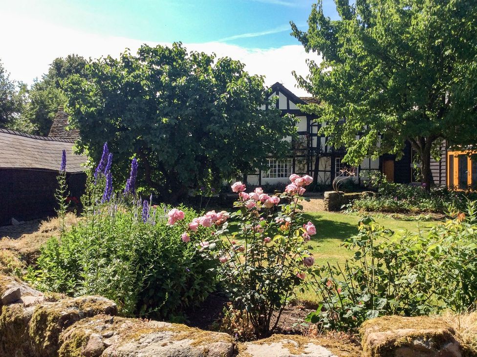 A flower garden with roses and trees at The Granary in Hereford