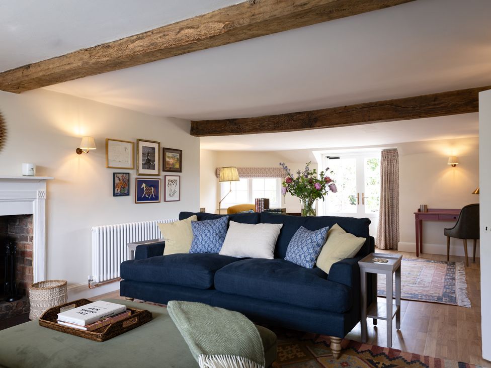 A living room with a sofa and flowers on a coffee table at Ambersham House in Midhurst