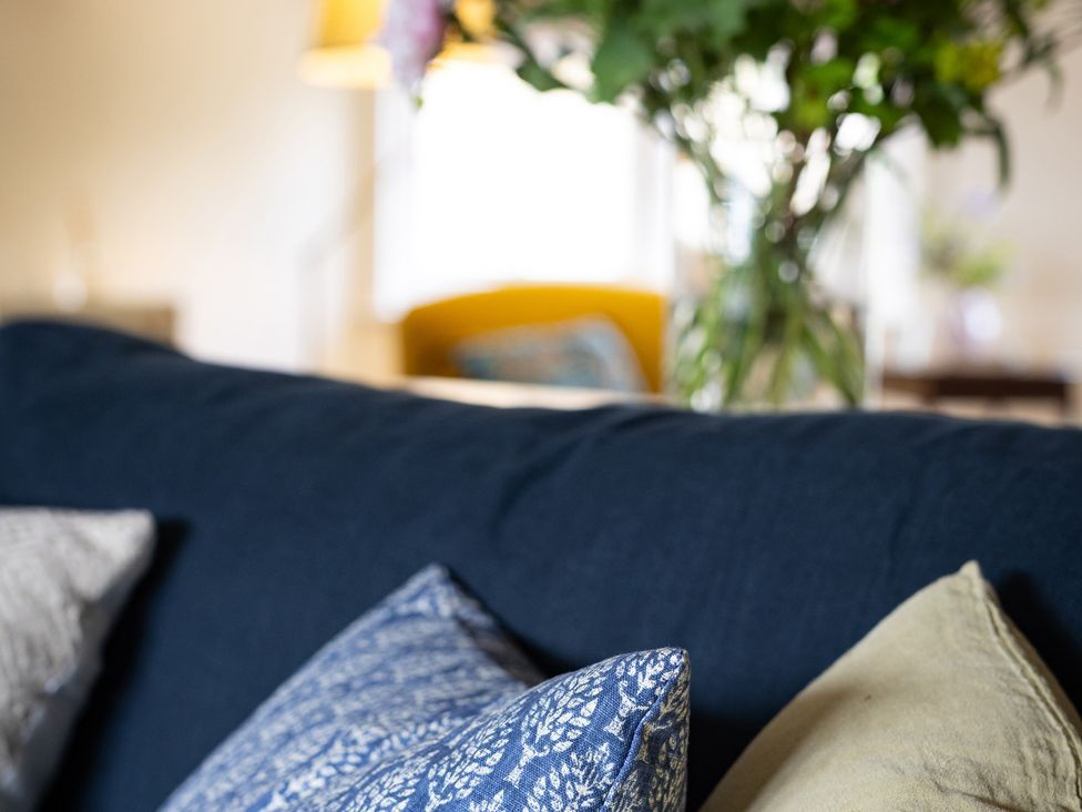 A sofa with cushions and a flower vase in Ambersham House Midhurst