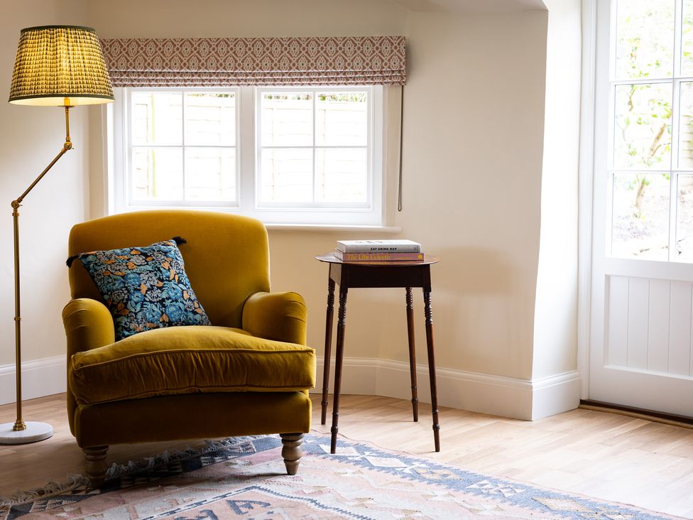 A living room with a yellow armchair and a standing lamp at Ambersham House in Midhurst