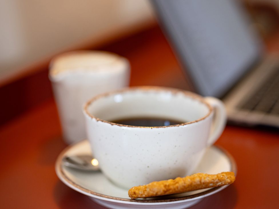 A cup of coffee with a cookie on a saucer at Ambersham House in Midhurst