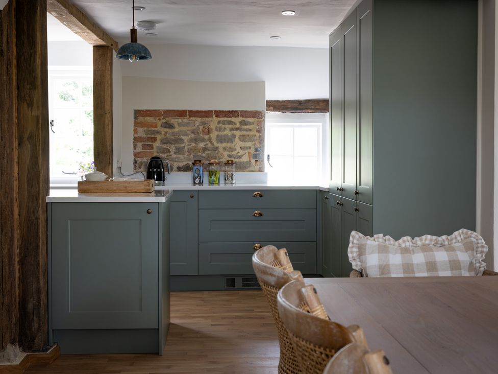 A kitchen with cabinets and a dining table at Ambersham House in Midhurst