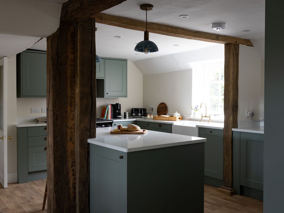 A kitchen with a central island and cabinets at Ambersham House in Midhurst
