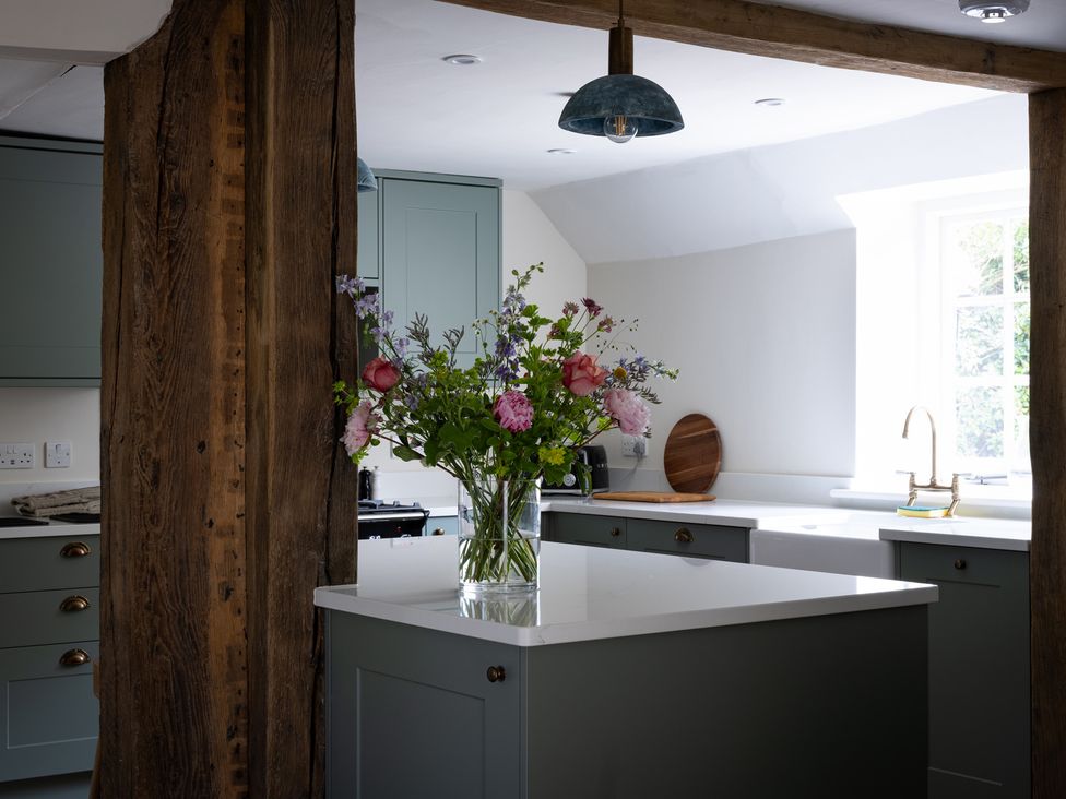 A kitchen with a central island and flowers at Ambersham House, Midhurst