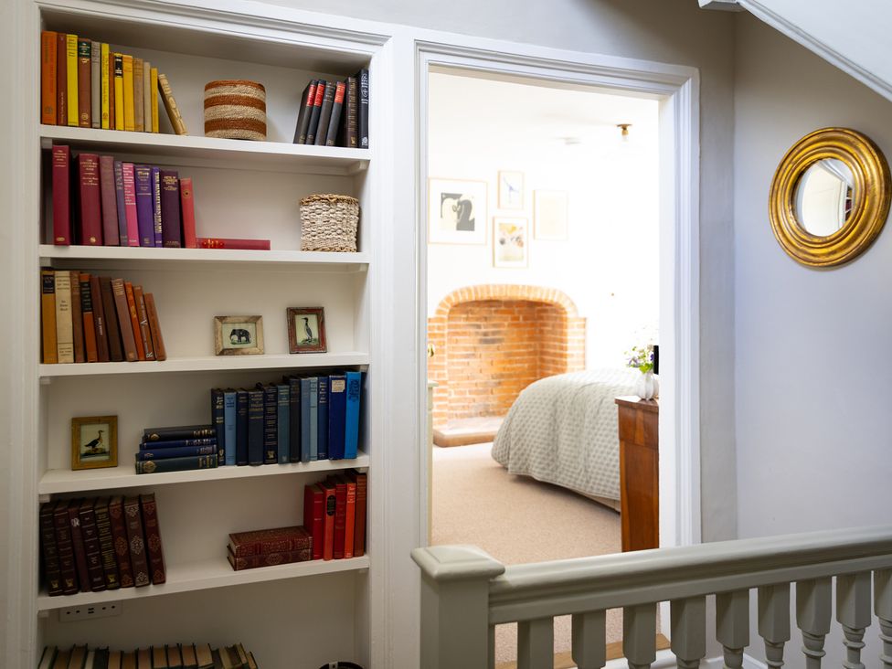 A hallway with a bookshelf and doorway leading to a bedroom at Ambersham House Midhurst