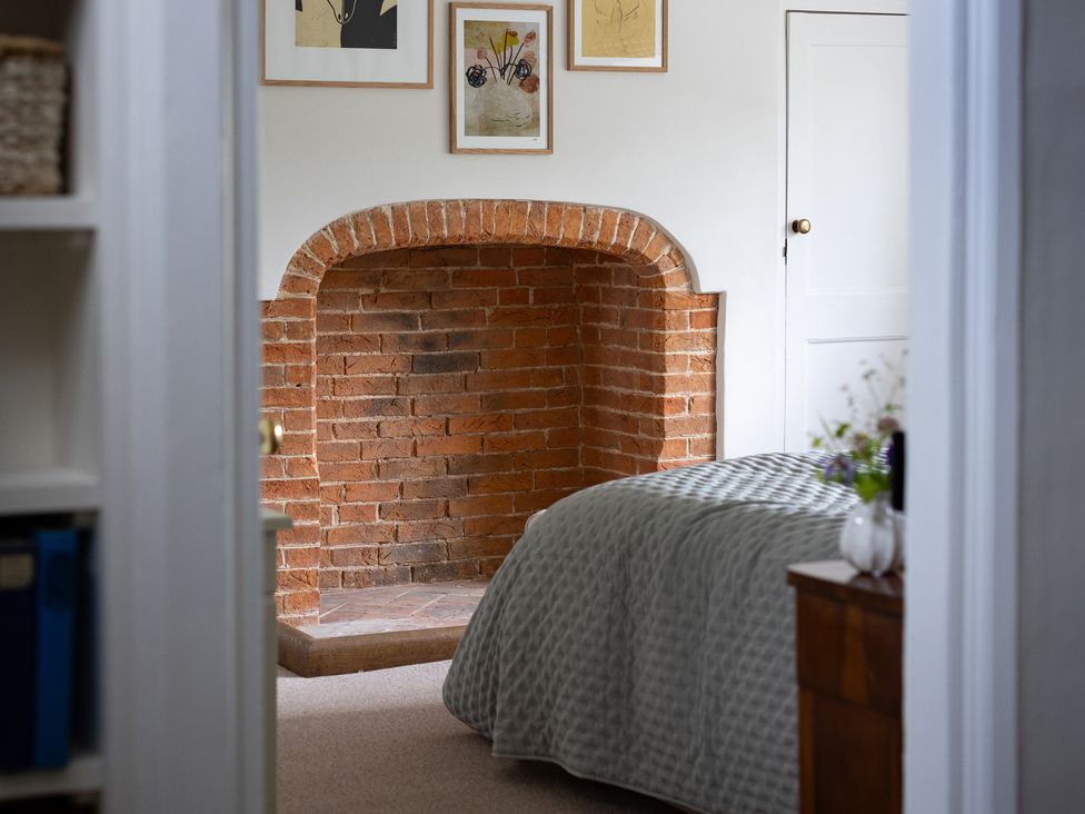 A bedroom with a brick alcove and art frames at Ambersham House in Midhurst
