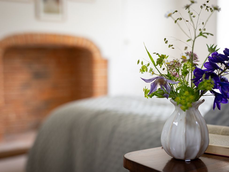 A vase with flowers on a table in a bedroom at Ambersham House in Midhurst