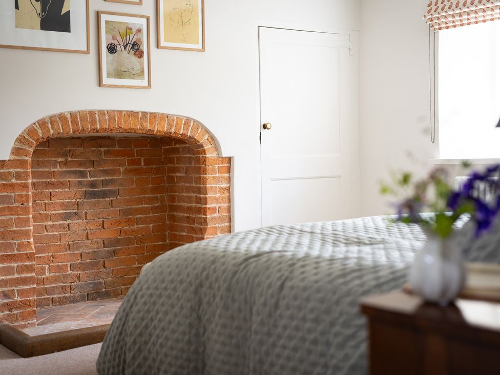 A bedroom with a fireplace and wall art at Ambersham House in Midhurst