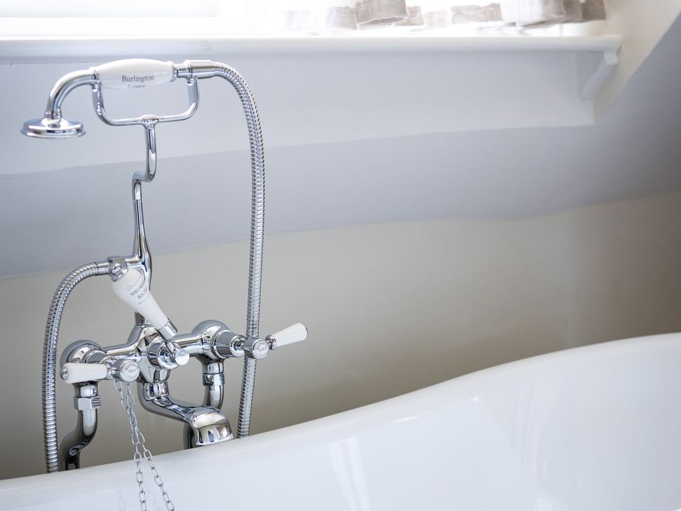 A bathtub with a faucet and showerhead at Ambersham House in Midhurst