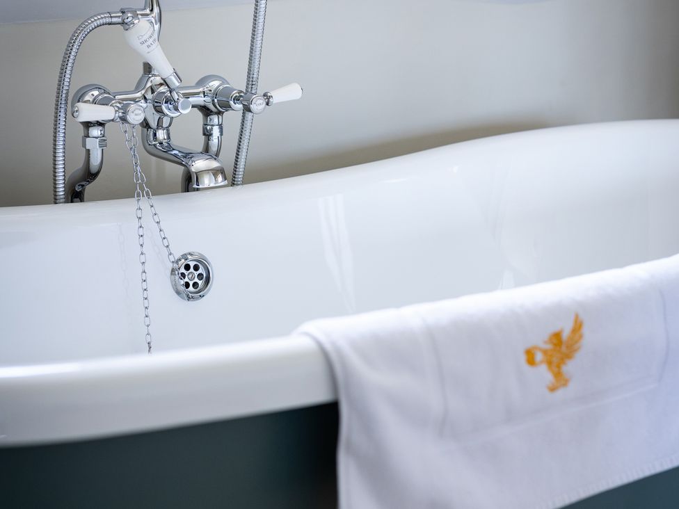 A bathtub with chrome fixtures and a towel at Ambersham House in Midhurst