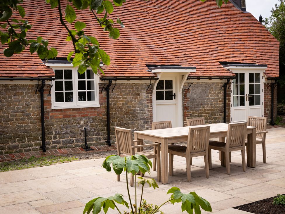 An outdoor seating area with a table and chairs at Ambersham House in Midhurst