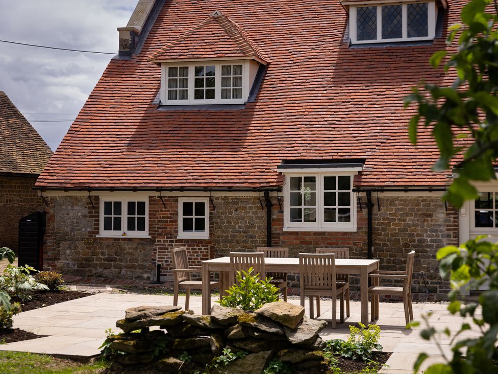 A patio area with a table and chairs at Ambersham House in Midhurst
