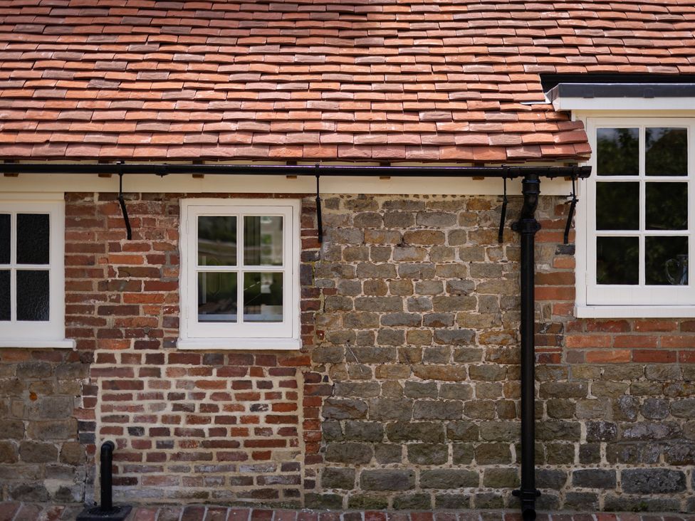 A brick and stone wall with windows at Ambersham House in Midhurst