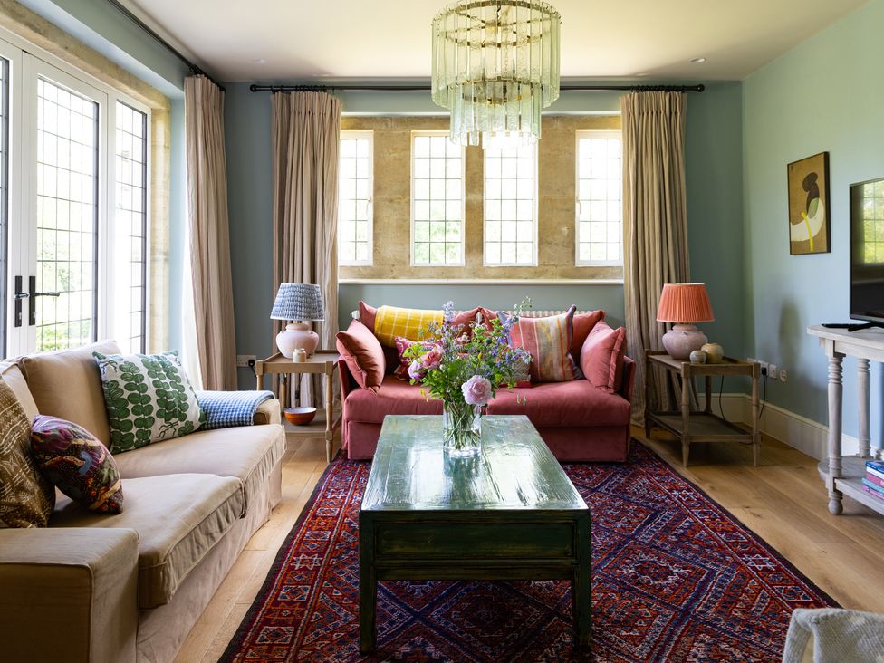 A living room with a sofa, coffee table, and vase of flowers at Costers Lodge in Midhurst