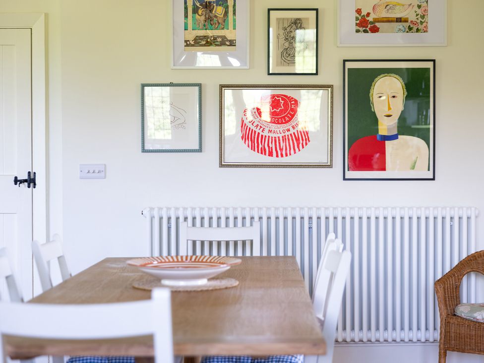 A dining room with a wooden table and wall art at Costers Lodge in Midhurst