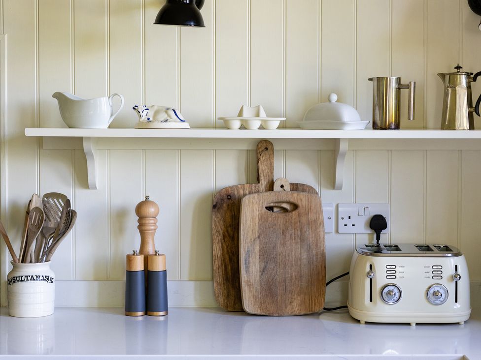A kitchen with a shelf of utensils and a toaster at Costers Lodge in Midhurst