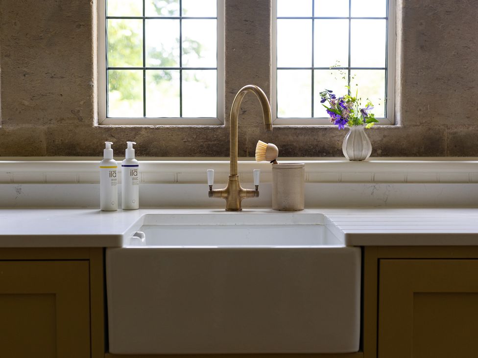 A kitchen sink and faucet with soap dispensers and a flower vase at Costers Lodge in Midhurst