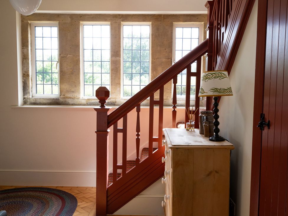 A hallway with a staircase and windows at Costers Lodge in Midhurst