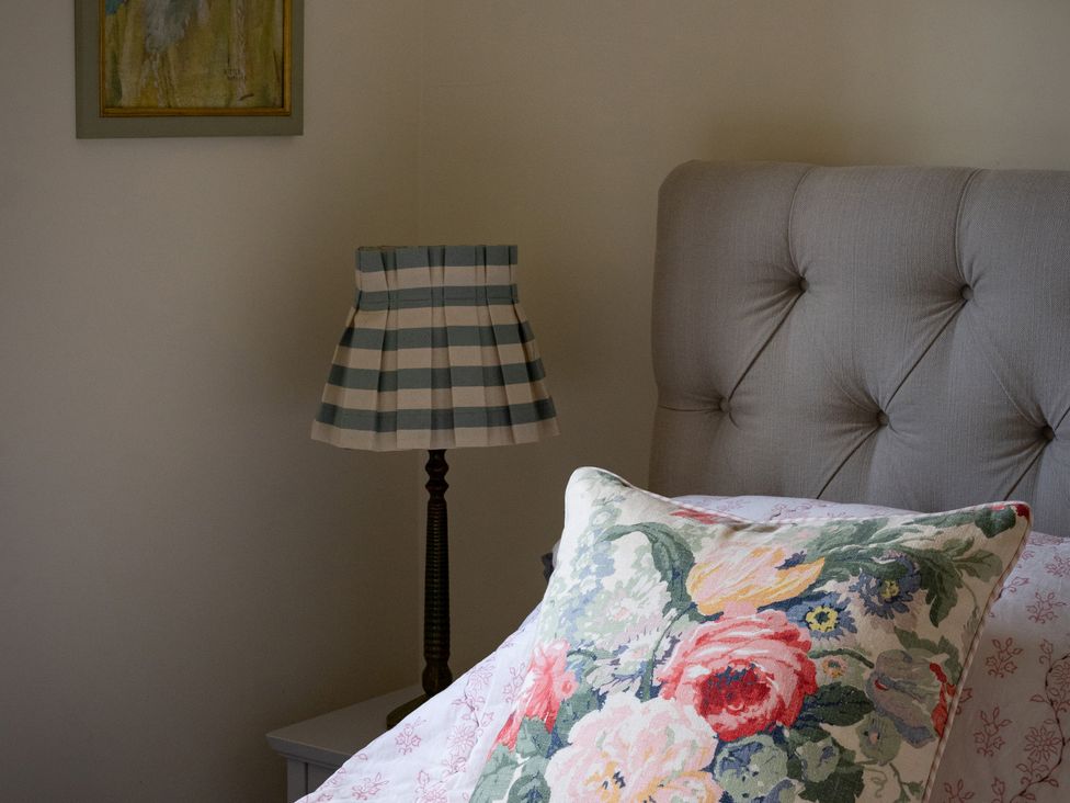 A bedroom with a bed, pillow, lamp, and painting at Costers Lodge, Midhurst