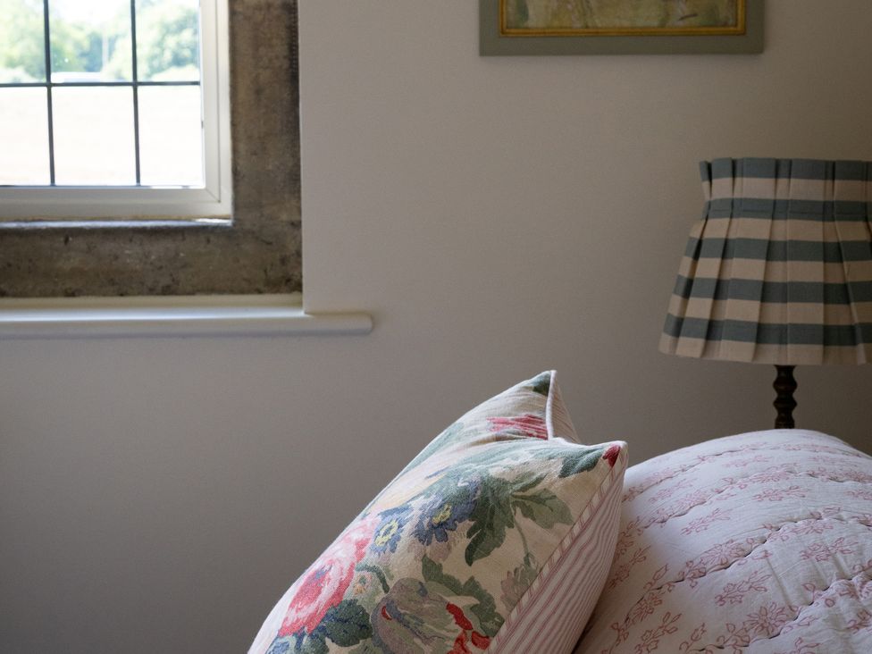 A bedroom with a window and decorative pillows at Costers Lodge in Midhurst