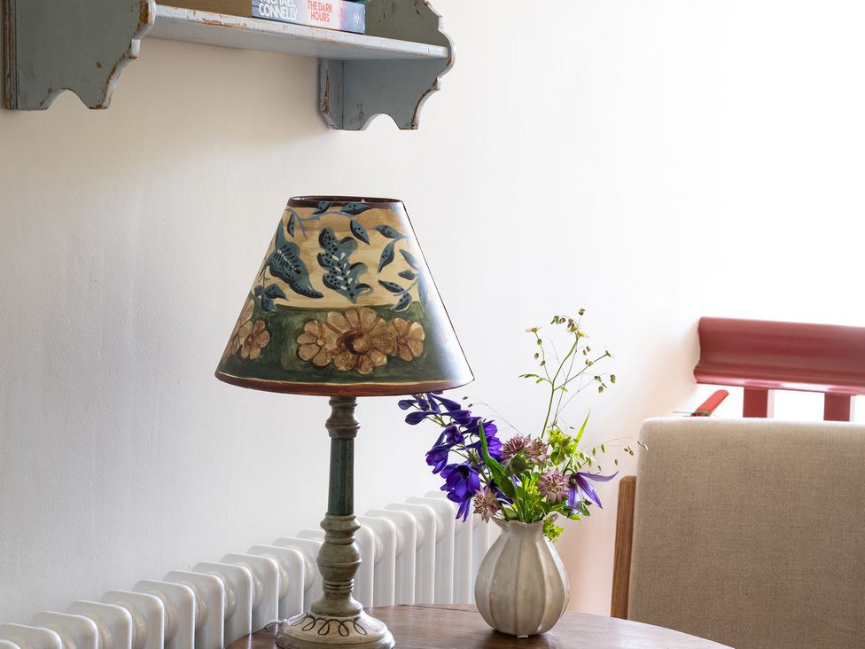 A living room with a lamp and flower vase at Costers Lodge in Midhurst