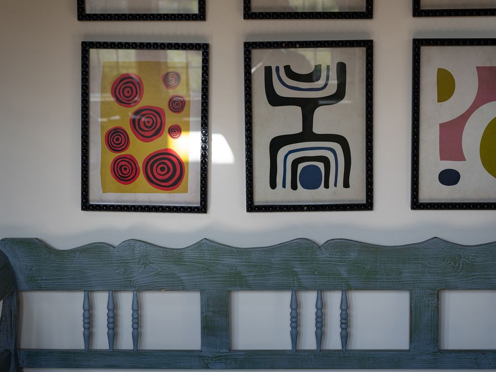 A wall with framed artworks and a bench at Costers Lodge in Midhurst
