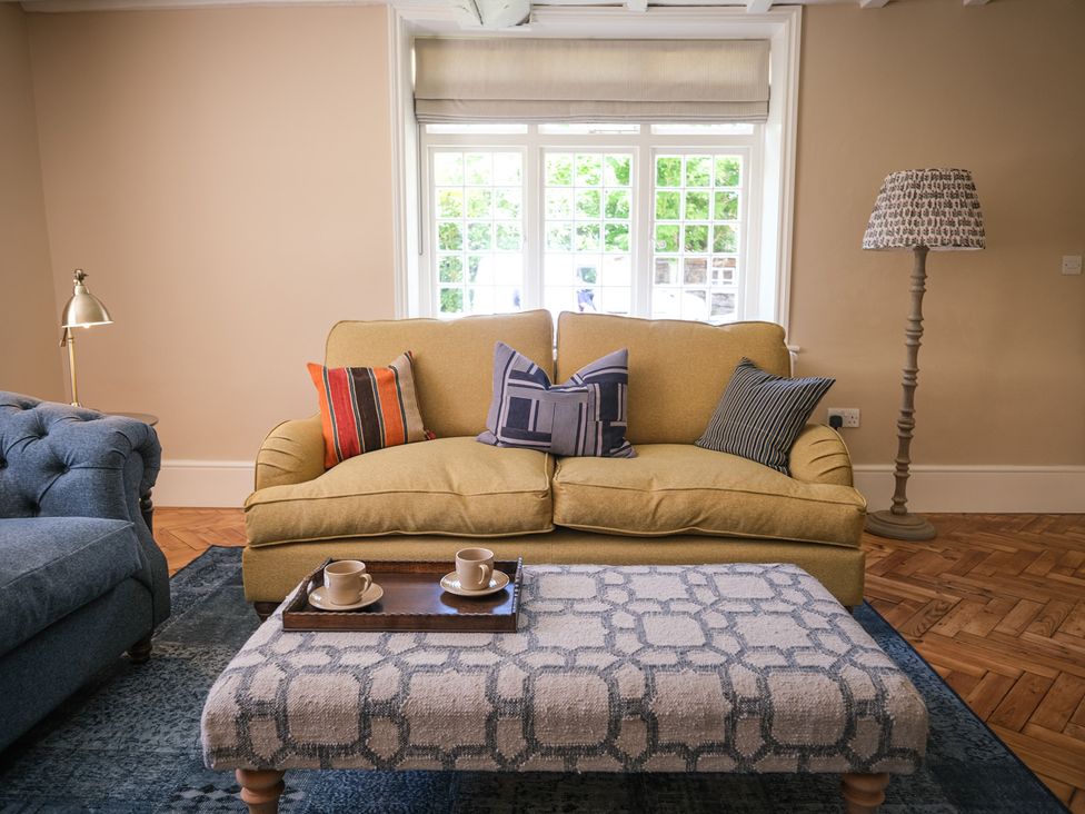 A living room with a yellow sofa and coffee table at Challens Yarde in Midhurst