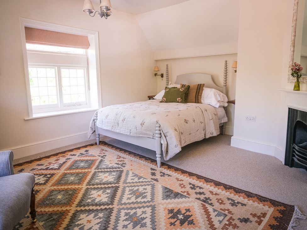 A bedroom with a bed, rug, and window at Challens Yarde in Midhurst