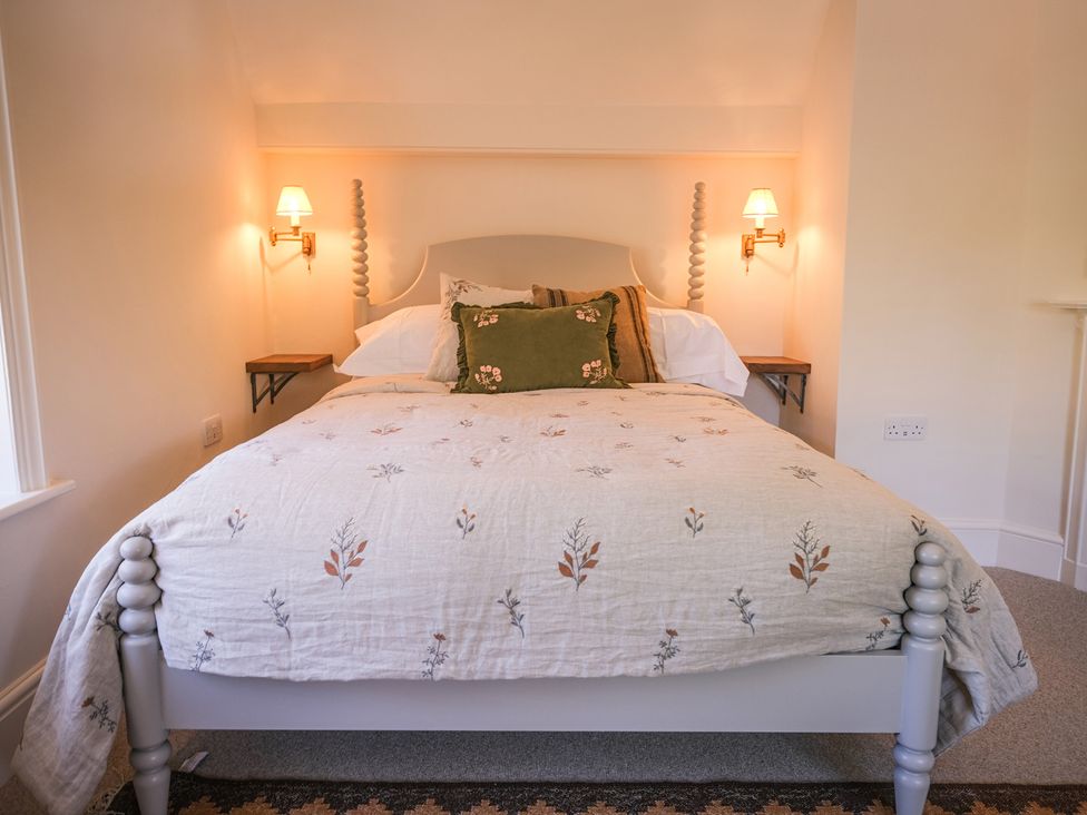 A bedroom with a bed, bedding, and wall sconces at Challens Yarde in Midhurst