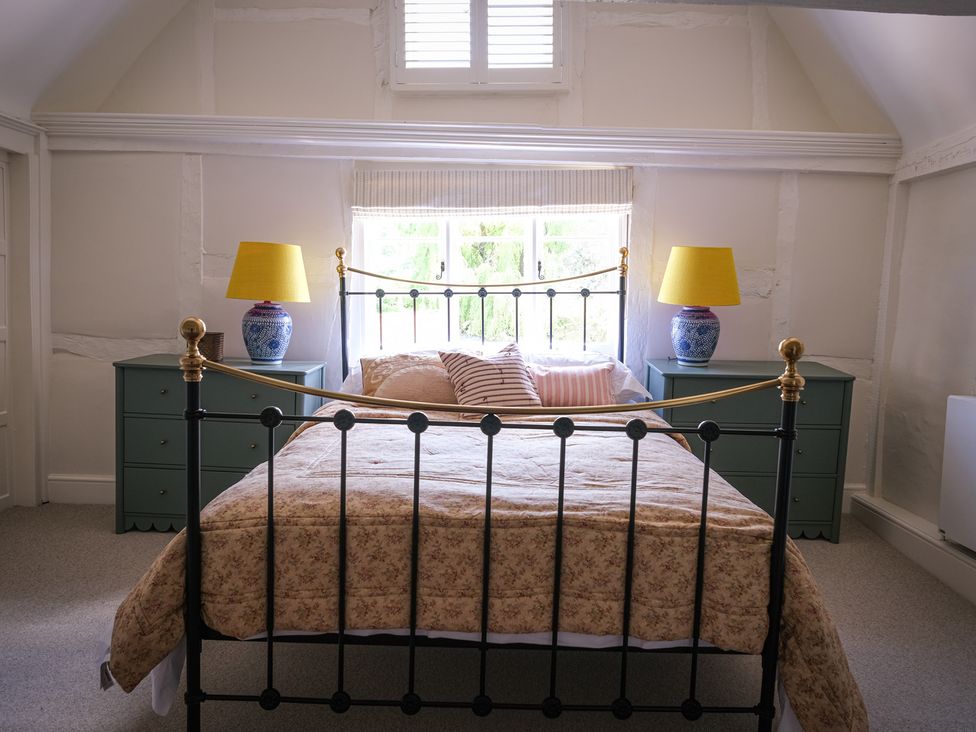 A bedroom with a bed, nightstands, and lamps at Challens Yarde in Midhurst