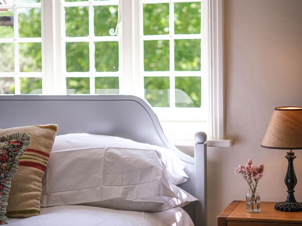 A bedroom with a bed, lamp, and window at Challens Yarde in Midhurst